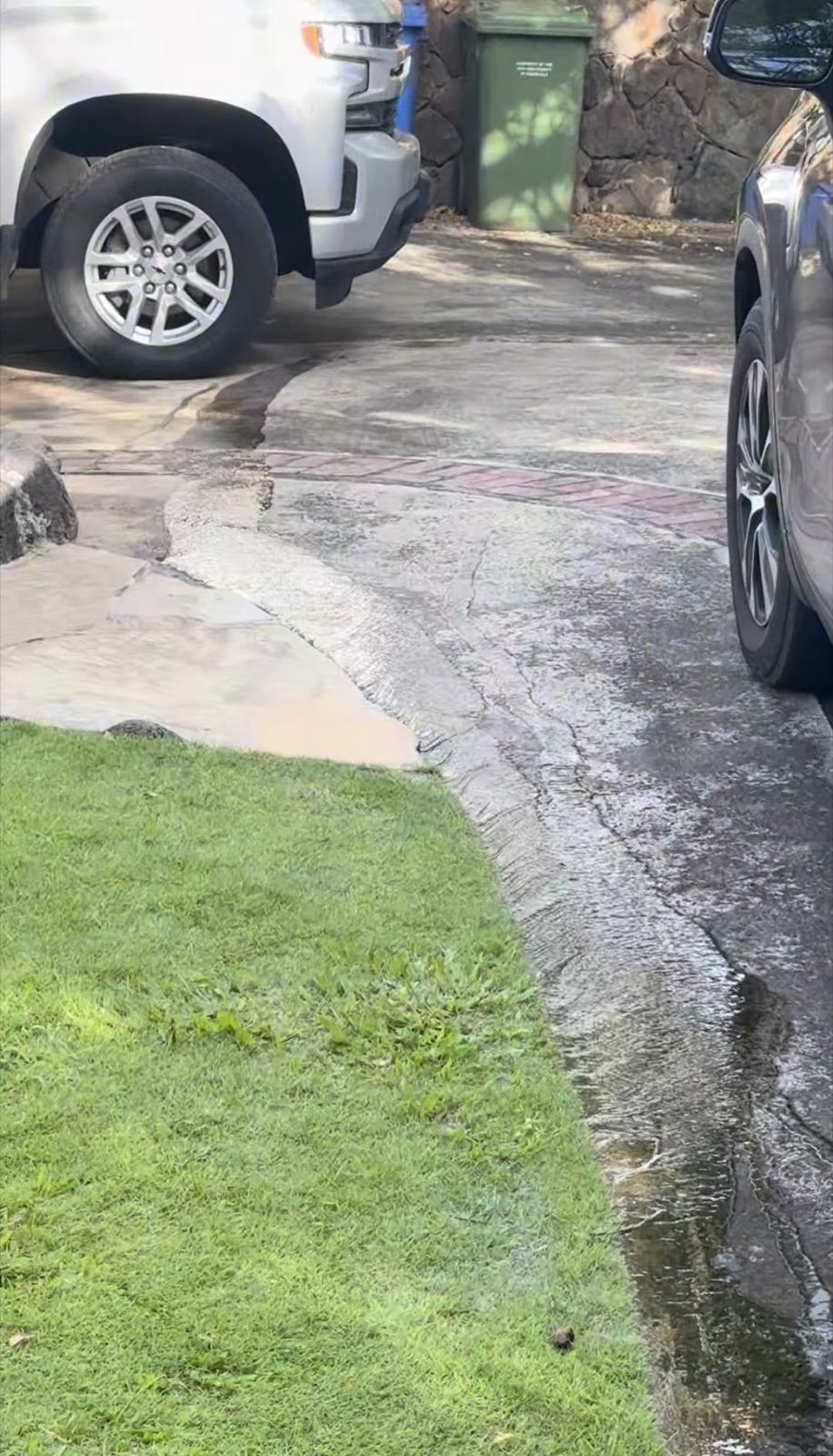 Irrigation water flowing from the lawn across the driveway at a beachfront Haleʻiwa home
